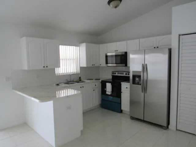 a kitchen with stainless steel appliances granite countertop a refrigerator a stove a sink and a microwave