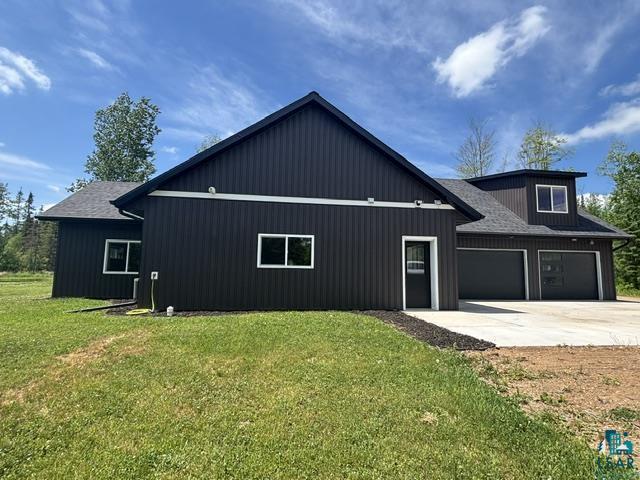 3454 Anderson Road Hibbing, MN 55746 - Photo 26 of 31 Modern exterior featuring dark vertical siding, a two-car garage with frosted glass panels, a dormer with a window, white window frames, and a concrete driveway