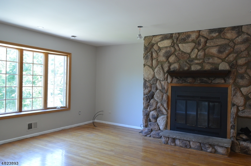 89 Forsythia Lane, Unit A Paramus, NJ 07652 - Photo 6 of 20 a view of an empty room with wooden floor and a fireplace