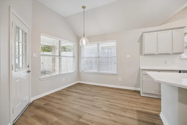 a view of an empty room with a window and wooden floor