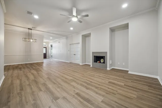 a view of an empty room with wooden floor and a fireplace