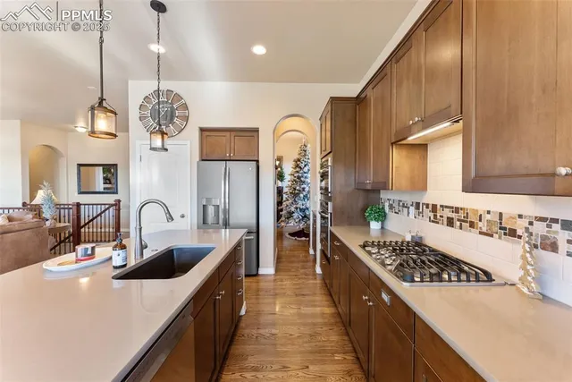 a large kitchen with stainless steel appliances granite countertop a sink a stove and a wooden cabinets