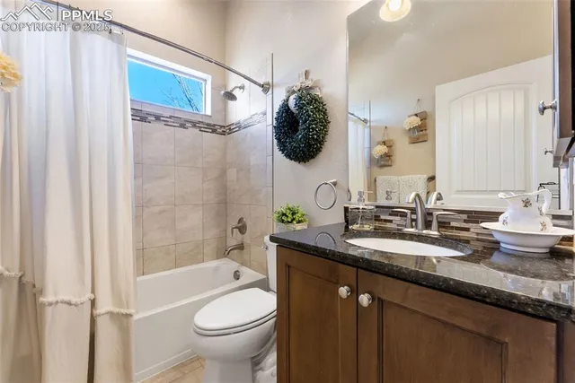 a bathroom with a granite countertop sink a toilet and shower