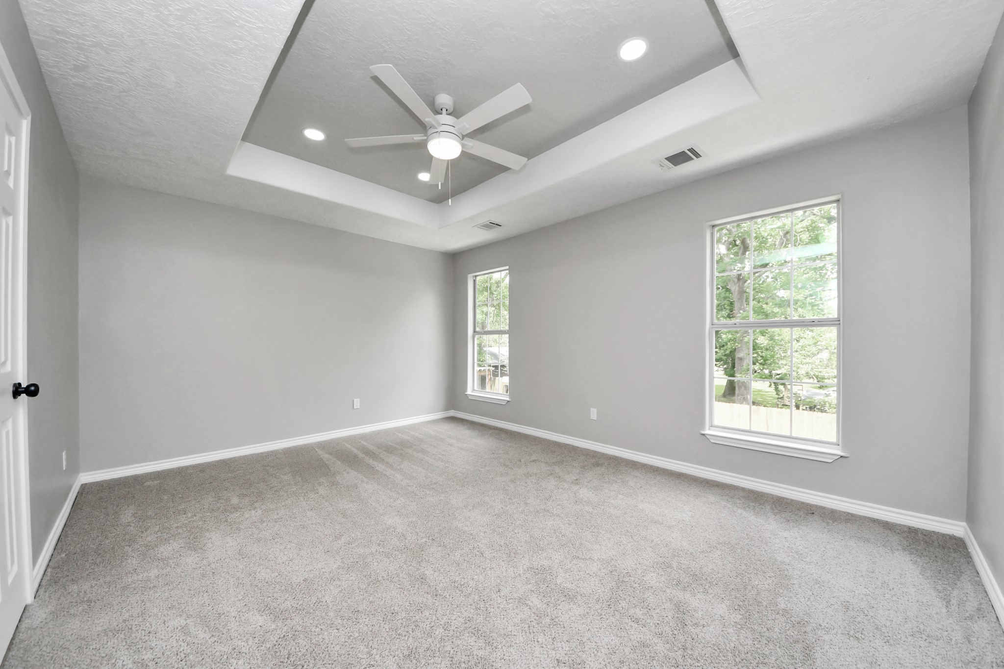 1105 East Kyle Road Clute, TX 77531 - Photo 22 of 44 The spacious primary bedroom has a tray ceiling, recessed lighting, and a ceiling fan. It has large windows providing natural light and is carpeted for comfort. It has a a bright and airy atmosphere.