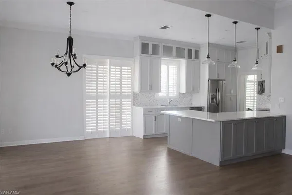 a kitchen with stainless steel appliances granite countertop a sink a window and white wooden cabinets