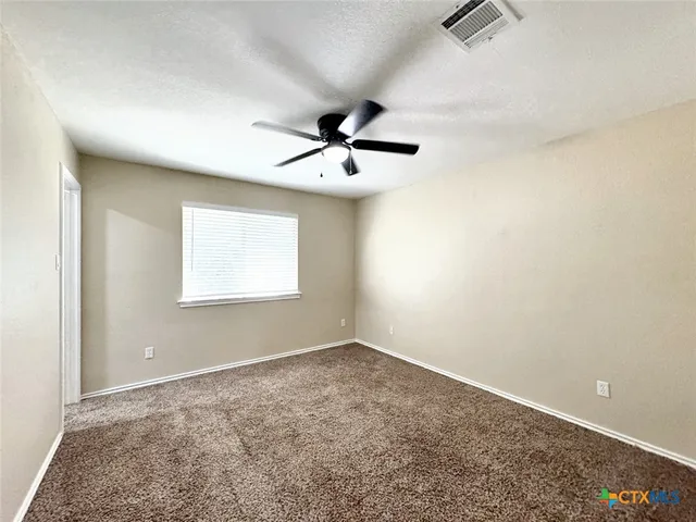 an empty room with a window and a ceiling fan