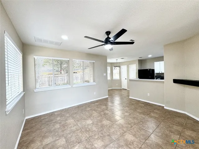 a view of an empty room with a window and a kitchen