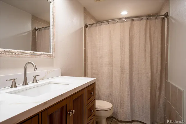 a bathroom with a sink a toilet a mirror and shower curtain