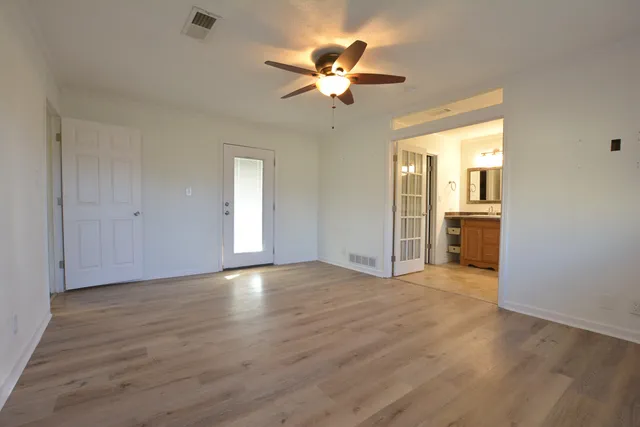 an empty room with wooden floor ceiling fan and window
