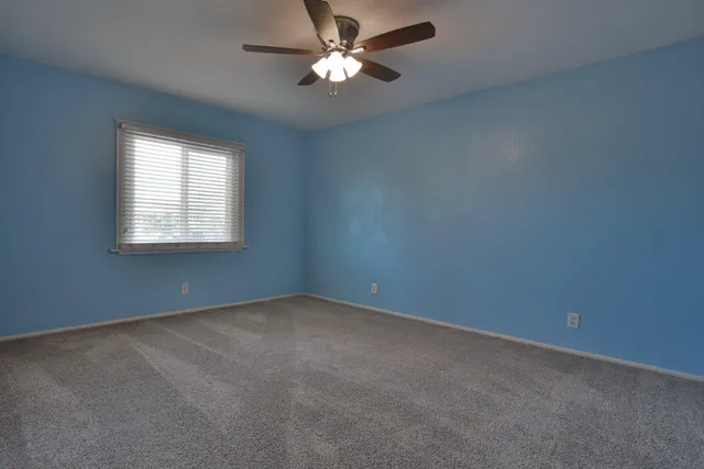 a view of an empty room with a ceiling fan and window