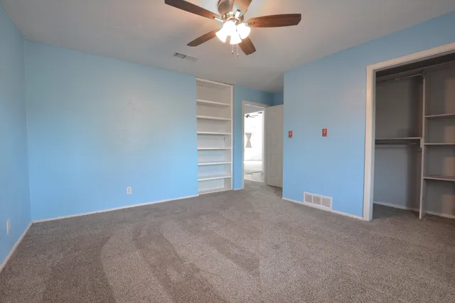 an empty room with a window and a fan