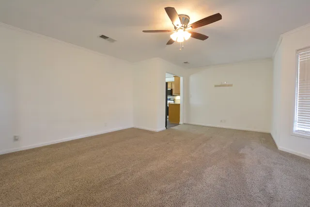 an empty room with windows and fan