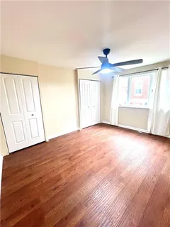 an empty room with wooden floor fan and windows