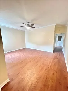 an empty room with wooden floor and fan