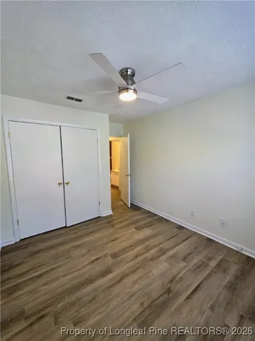 an empty room with wooden floor ceiling fan and windows