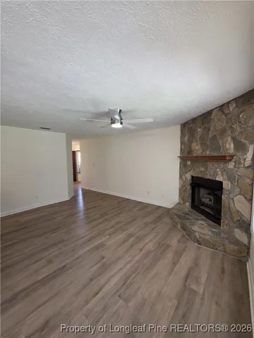 an empty room with wooden floor fireplace and windows