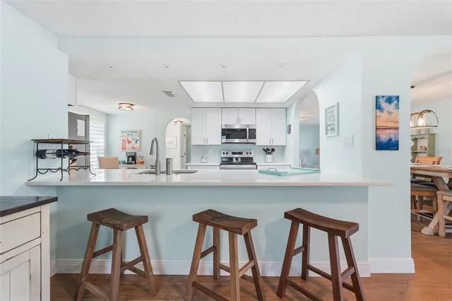 a kitchen with stainless steel appliances a dining table chairs and a refrigerator