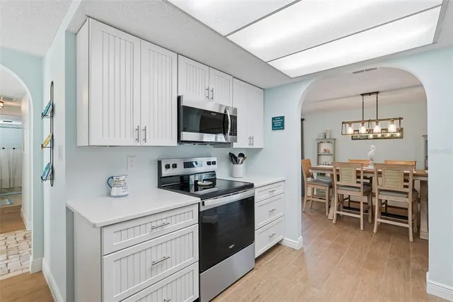 a kitchen with stainless steel appliances a stove top oven a sink a dining table and chairs