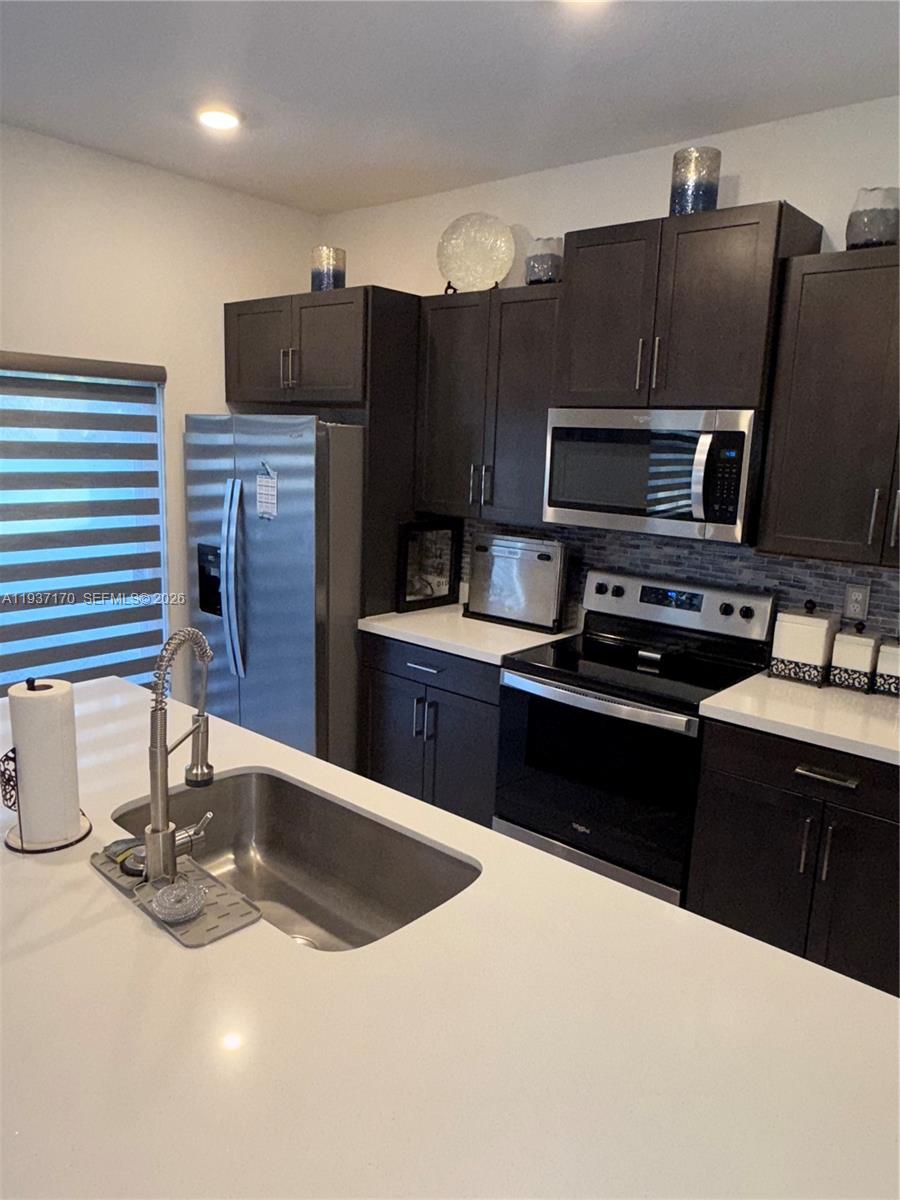 818 South E 19th Street, Unit 818 Homestead, FL 33034 - Photo 7 of 10 a kitchen with stainless steel appliances kitchen island granite countertop a refrigerator and a stove top oven