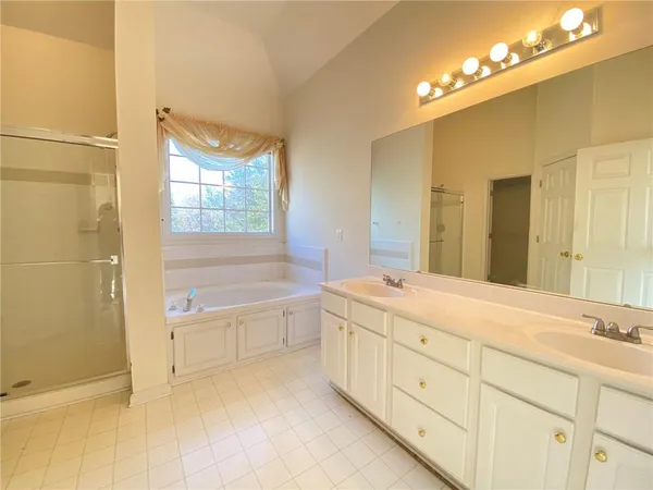 a spacious bathroom with a double vanity sink a mirror and a bathtub