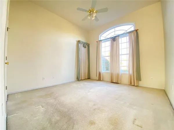 an empty room with windows and ceiling fan
