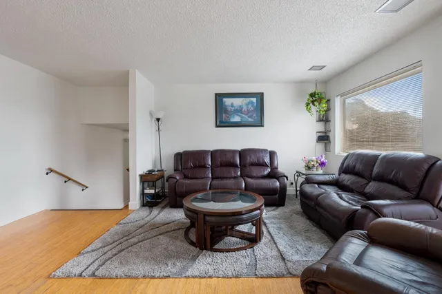 a kitchen with stainless steel appliances granite countertop a stove top oven a refrigerator a sink and a dining table with wooden floor