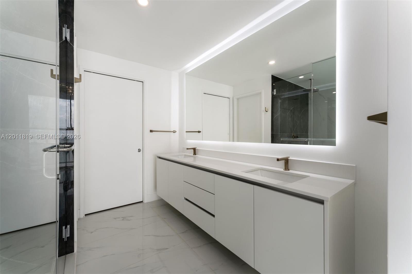 700 Northeast 24th Street, Unit 2504 Miami, FL 33137 - Photo 23 of 52 Spa-inspired primary bathroom featuring dual vanities, a deep soaking tub, a frameless glass rainfall shower, and designer porcelain tile throughout.