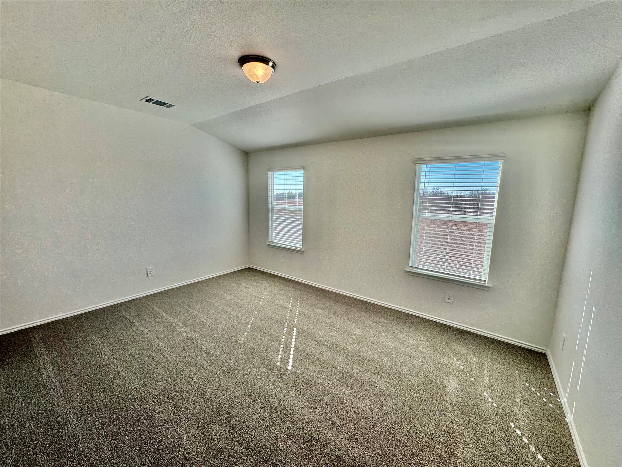 104 Calcite Road, Unit 3 Kyle, TX 78640 - Photo 4 of 7 Carpeted spare room with a textured ceiling, a textured wall, and vaulted ceiling