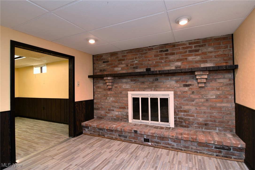 317 Nobottom Road Berea, OH 44017 - Photo 34 of 49 Unfurnished living room with a fireplace, brick wall, hardwood / wood-style floors, and a drop ceiling