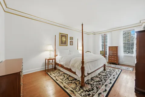 a bedroom with a bed rug and wooden floor