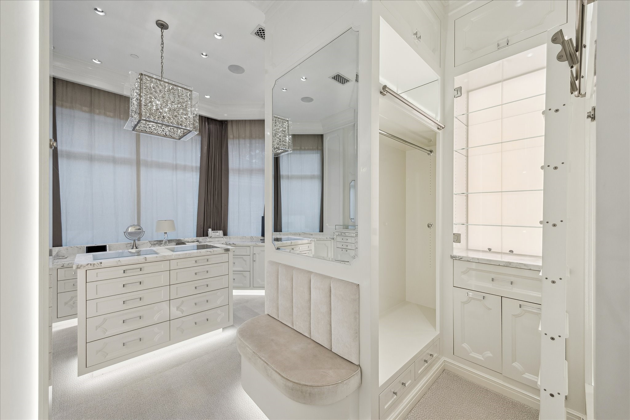 220 Merrie Way Lane Houston, TX 77024 - Photo 26 of 50 The boutique-inspired closet features lacquered millwork, three hanging levels, backlit display shelves, and a marble-topped island with felt-lined drawers—complete with a bay window framing th pool and backyard views.