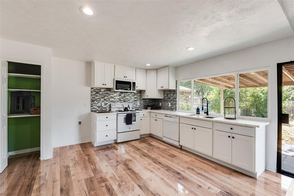9324 County View Road Dallas, TX 75249 - Photo 18 of 24 a kitchen with granite countertop white cabinets and white appliances
