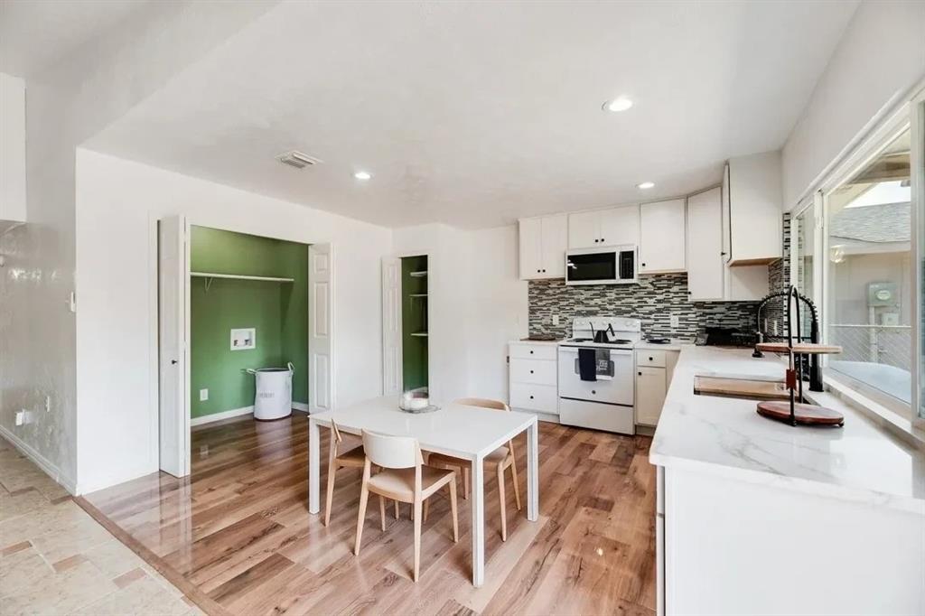 9324 County View Road Dallas, TX 75249 - Photo 10 of 24 a kitchen with stainless steel appliances kitchen island granite countertop a refrigerator a stove a sink dishwasher and white cabinets with wooden floor
