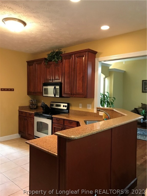 5220 Spreading Branch Road Hope Mills, NC 28348 - Photo 2 of 17 a kitchen with kitchen island granite countertop wooden cabinets a stove and a sink