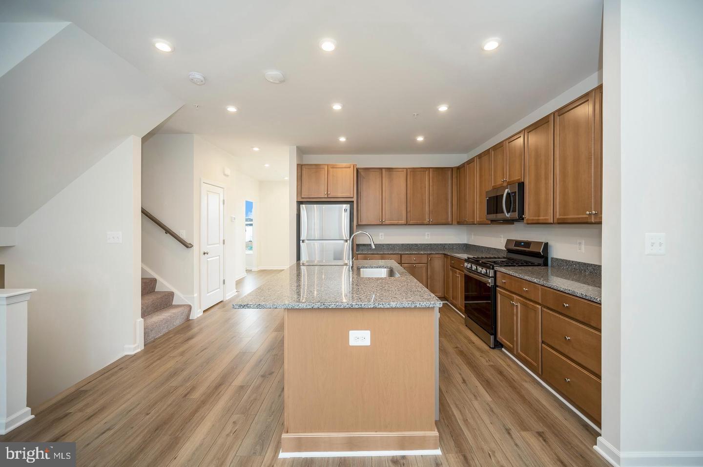 360 Coastal Avenue, Unit 102 Stafford, VA 22554 - Photo 8 of 25 a large kitchen with stainless steel appliances kitchen island granite countertop a stove a sink and a refrigerator