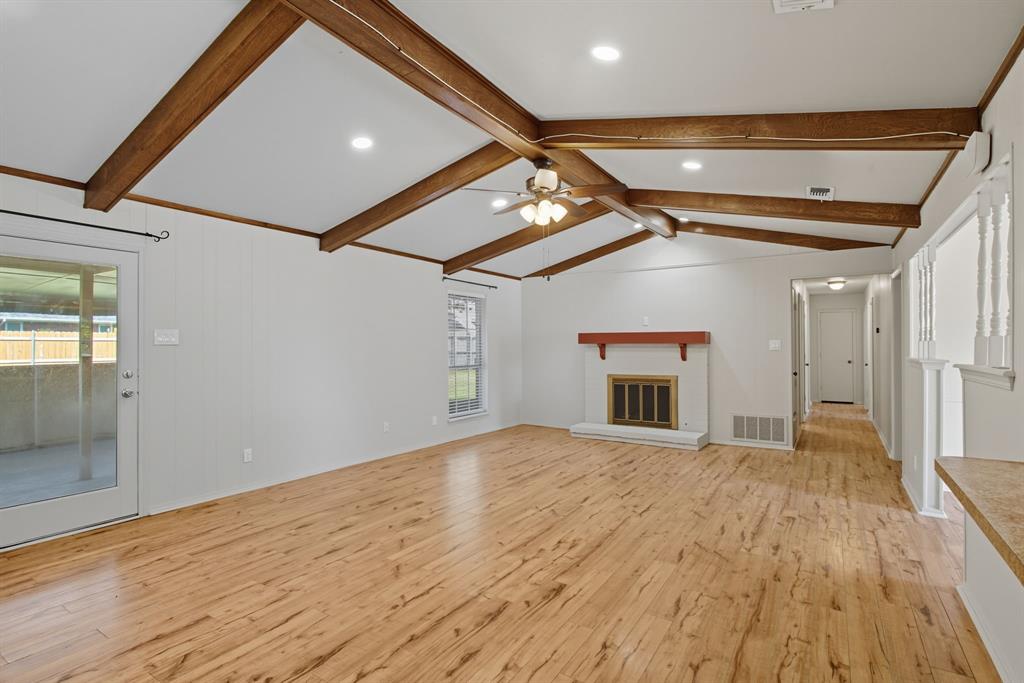 10304 Oak Creek Drive Greenville, TX 75402 - Photo 6 of 25 en empty room with wooden floor and fireplace