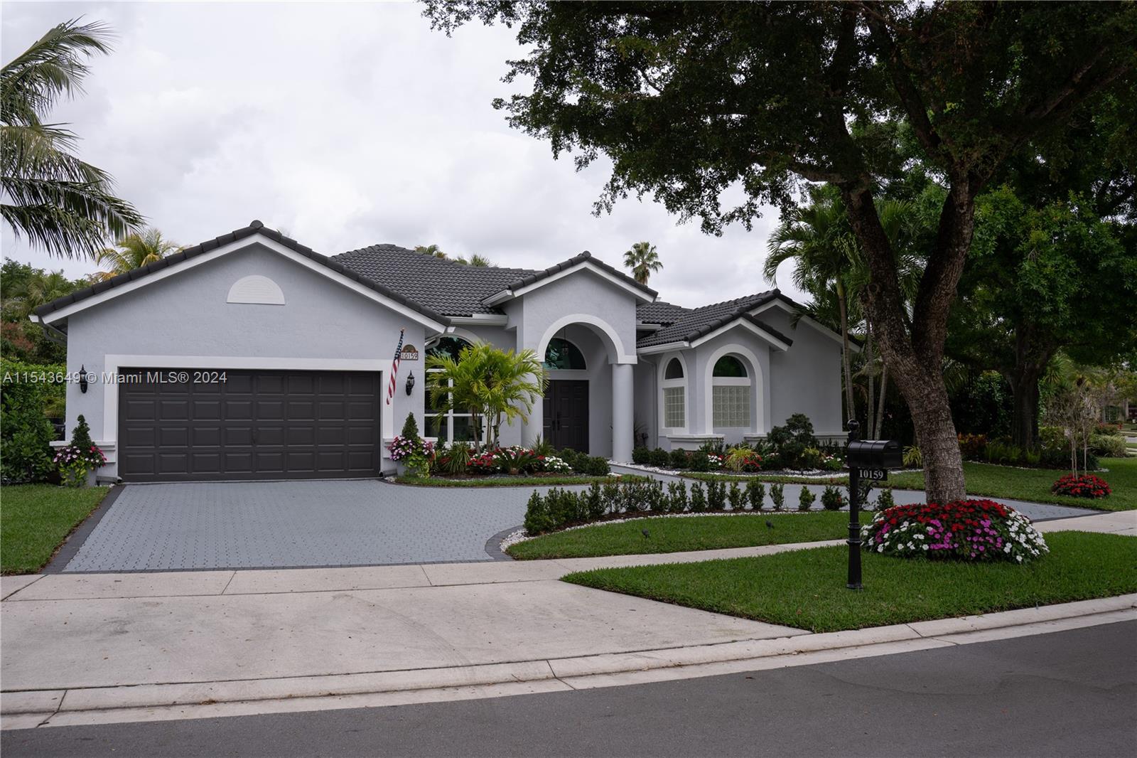 10159 Umberland Place Boca Raton, FL 33428 - Photo 2 of 25 a front view of a house with a garden and trees