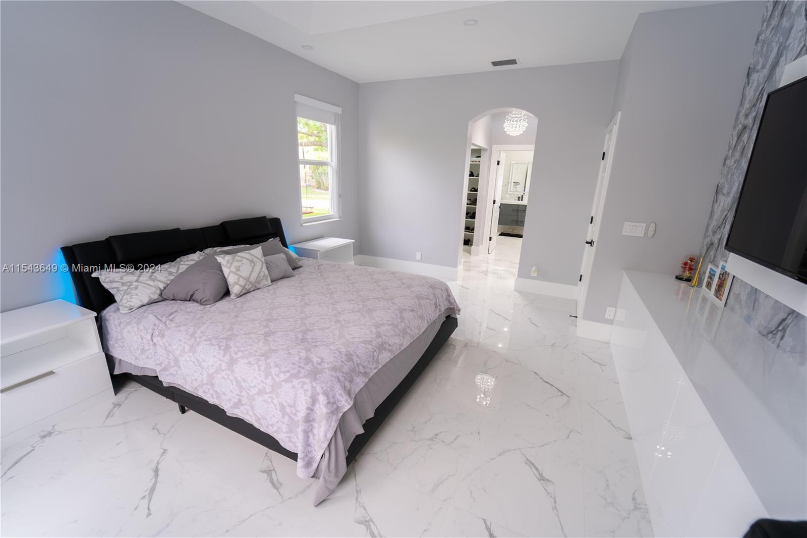 10159 Umberland Place Boca Raton, FL 33428 - Photo 10 of 25 a bedroom with a bed and a flat tv screen on a dresser