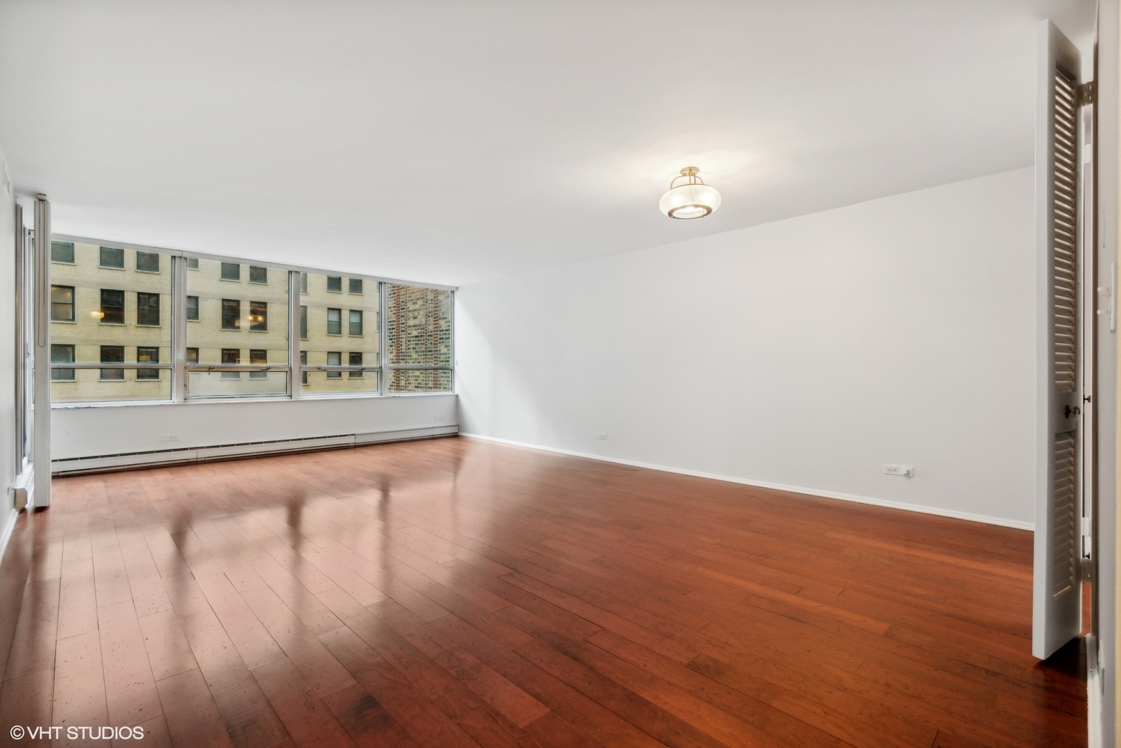 201 East Chestnut Street, Unit 10E Chicago, IL 60611 - Photo 2 of 12 wooden floor in a hall with an empty room