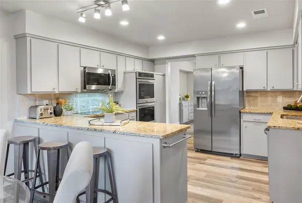 a kitchen with kitchen island a refrigerator stove microwave and cabinets