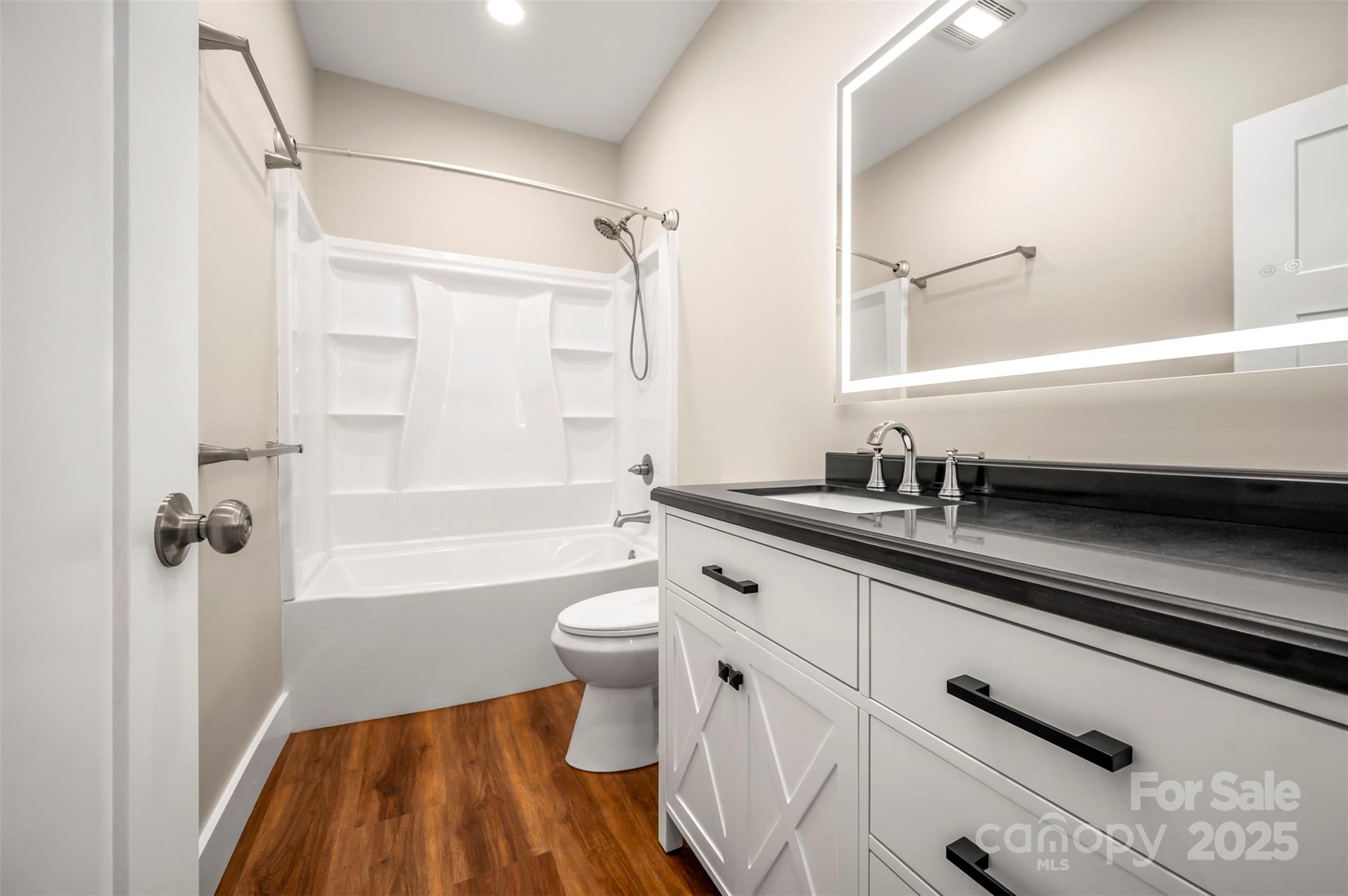 213 Calhoun Street Hendersonville, NC 28739 - Photo 24 of 32 a bathroom with a granite countertop sink a toilet a mirror and bathtub