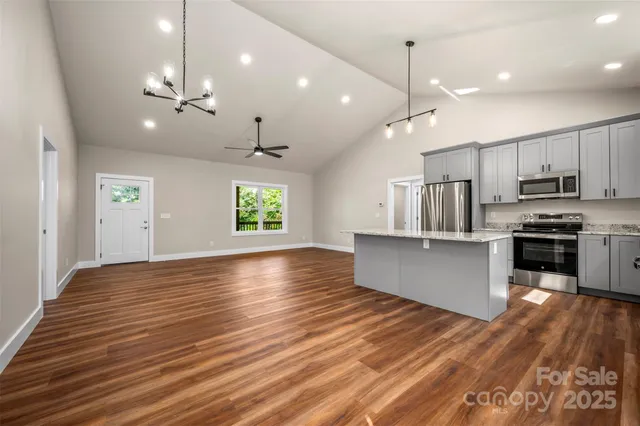 a kitchen with stainless steel appliances kitchen island granite countertop a stove a refrigerator and a wooden floors