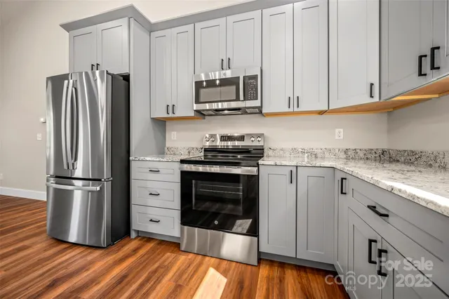 a kitchen with granite countertop a refrigerator stove and white cabinets