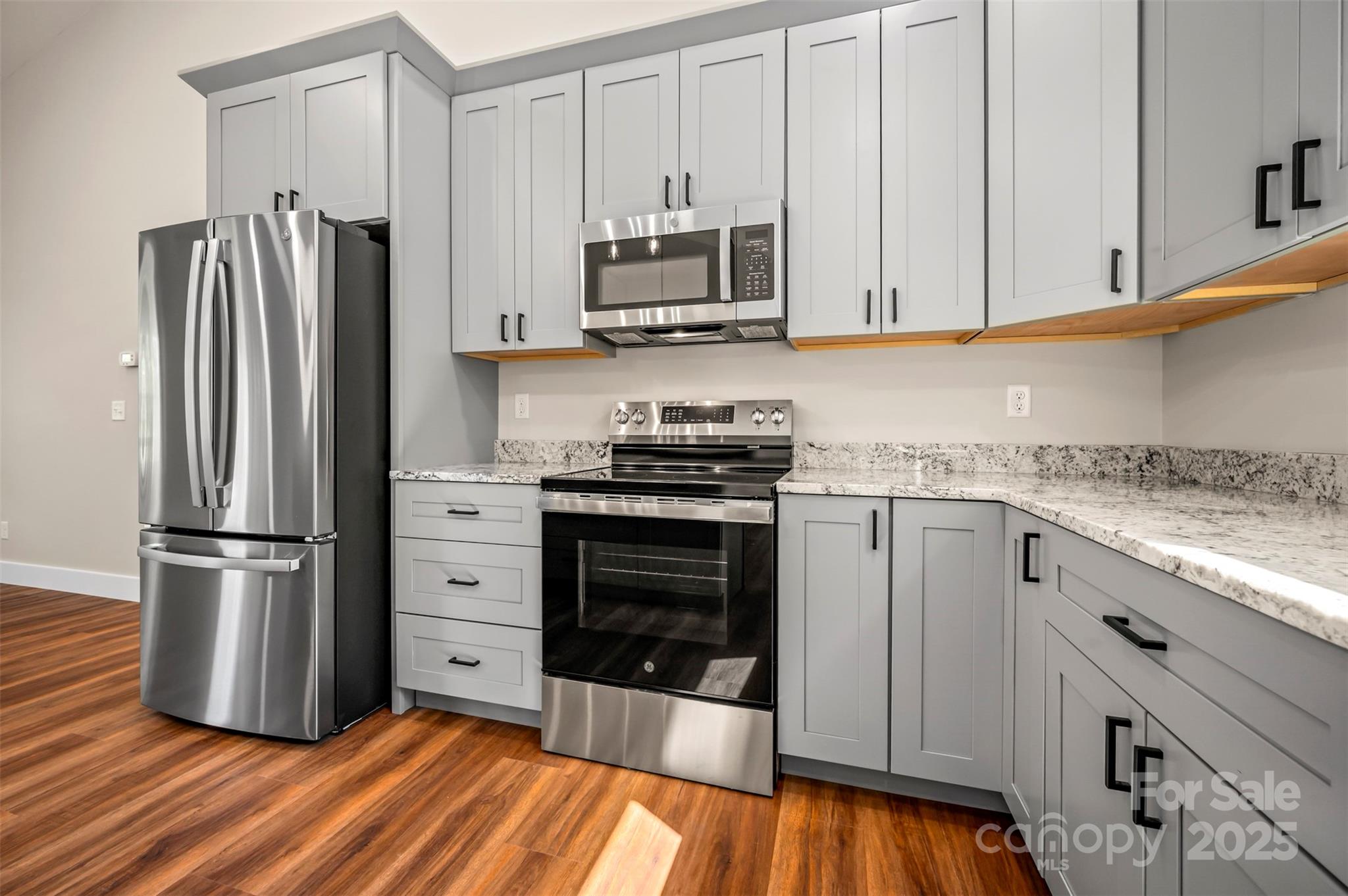 213 Calhoun Street Hendersonville, NC 28739 - Photo 10 of 32 a kitchen with granite countertop a refrigerator stove and white cabinets