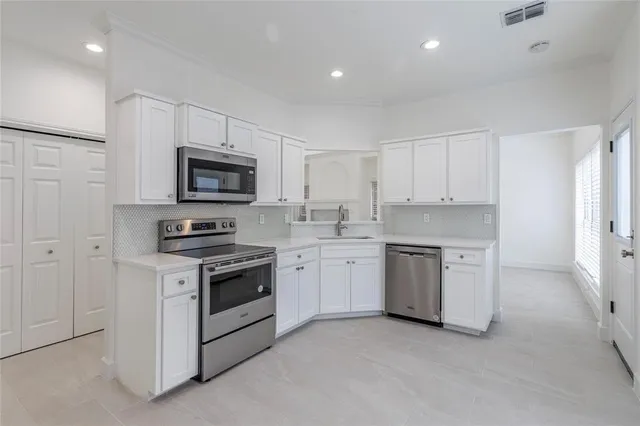 a kitchen with white cabinets and stainless steel appliances