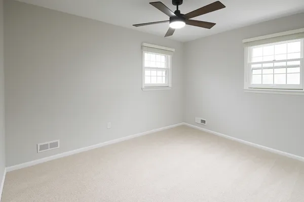 an empty room with a window and a fan