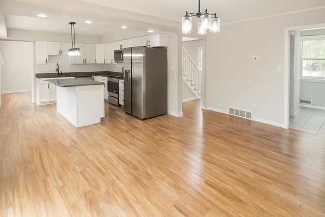 a kitchen with stainless steel appliances granite countertop a refrigerator a sink dishwasher and a wooden floor