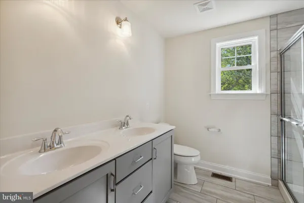 a bathroom with a toilet a sink a mirror and a window