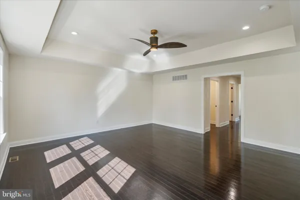 an empty room with wooden floor fan and windows