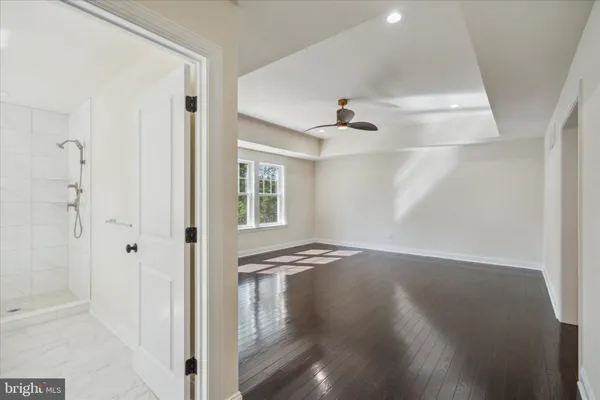 a view of empty room with wooden floor and fan